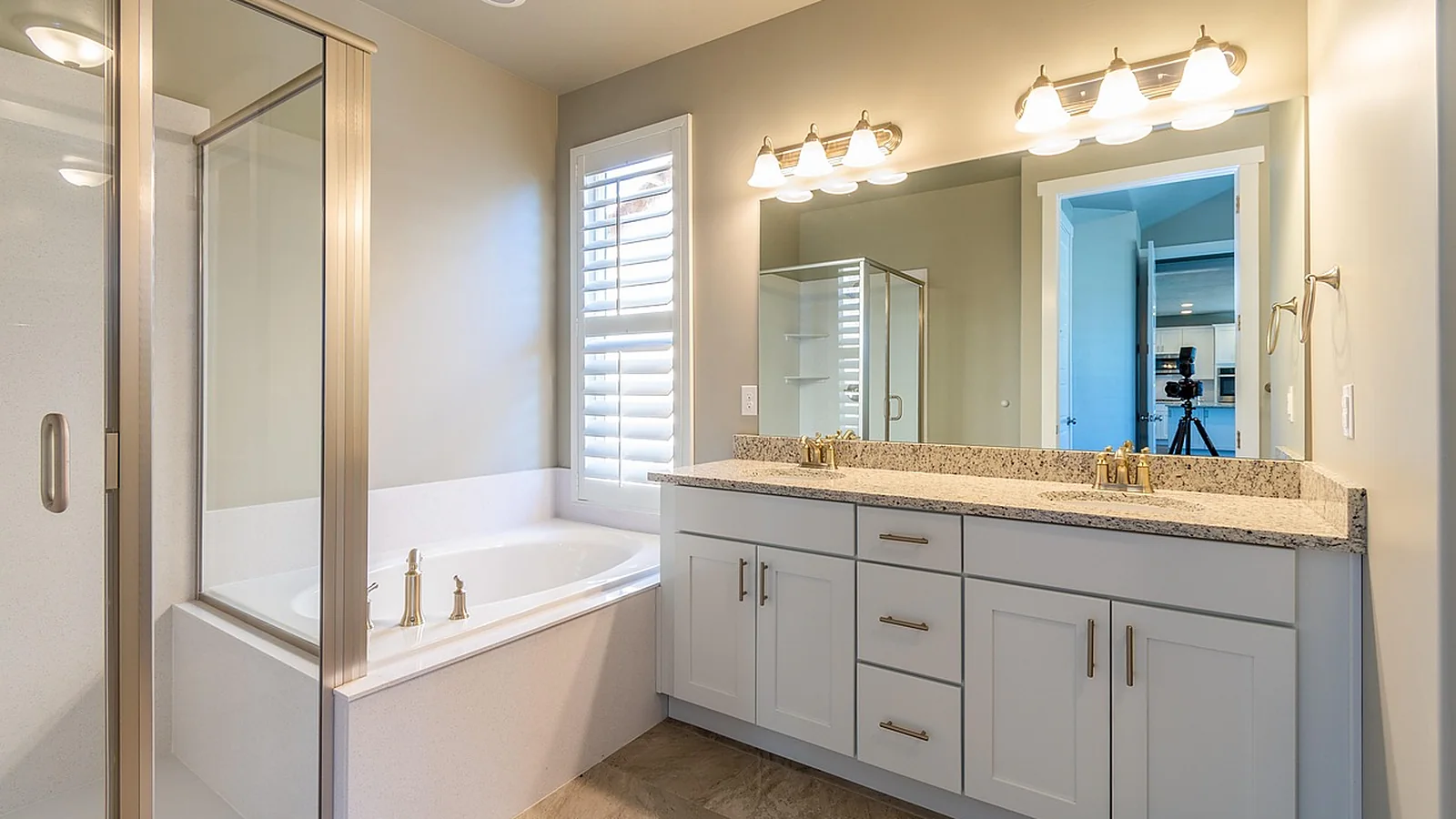 Bathroom with a white double vanity, stone countertop, framed mirror and a glass shower enclosure