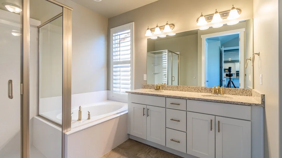 Bathroom with a white double vanity, stone countertop, framed mirror and a glass shower enclosure
