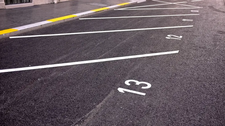 Freshly painted white parking stall lines and numbers on clean asphalt