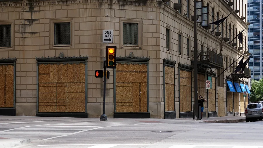 Downtown corner building with its storefront windows covered in plywood