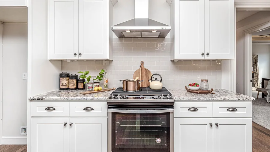 Kitchen with white shaker cabinets, a stainless range with hood and a stone countertop