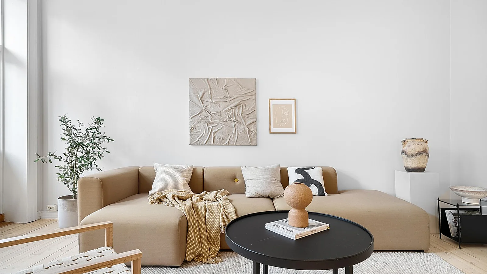 Living room with a beige sofa, wood coffee table and daylight from a large window